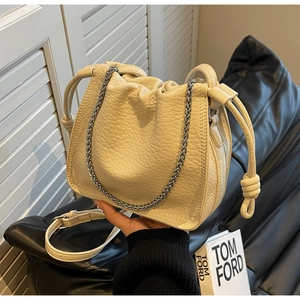 Close-up of cream pleated bucket bag with lychee texture and silver chain strap