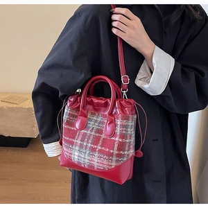 Détail du sac seau en tweed à carreaux rouges avec poignée en cuir PU et cordon