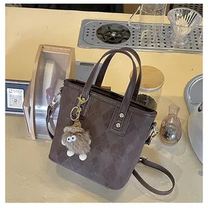 Detail of coffee brown quilted tote bag with a cute plush monster charm on a cafe bar