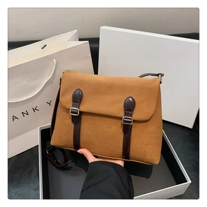 Detail of retro messenger bag showing faux suede texture and brown leather straps