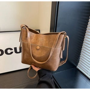 Detailed close-up of brown vintage leather bucket bag with retro round buckle and drawstring