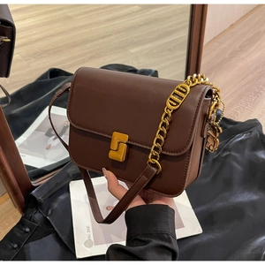 Detail of dark brown crossbody bag with gold square twist lock and metal bear charm