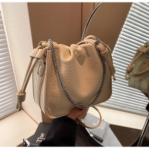 Detail of beige bucket bag with pleated drawstring closure and silver chain strap
