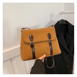 Macro detail of brown frosted suede tote bag featuring vintage gold buckles and straps