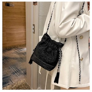 Detail of black glitter bucket bag with stylish long tassels and metal chain strap