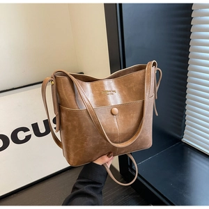 Detail of vintage brown bucket bag showing matte PU leather texture and shoulder strap