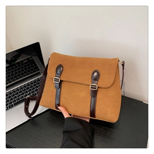 Detail of vintage brown suede tote bag featuring metallic buckles and crossbody strap