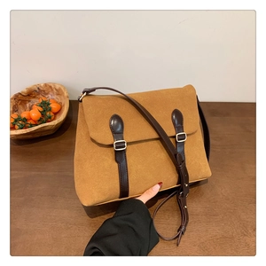 Detail of vintage matte brown tote bag with leather straps and golden buckles on a table