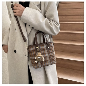Retro plaid tweed bucket bag with leather trim and plush doll charm shown on model