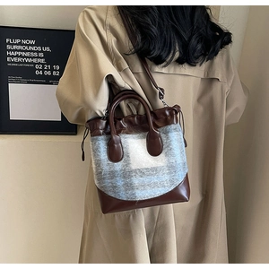 Détail du cuir marron et du tissu en peluche à carreaux gris sur un sac seau
