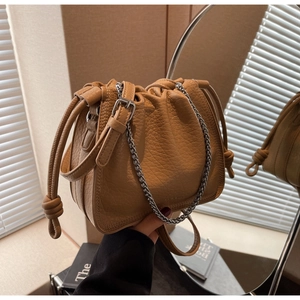 Close-up of pebble leather bucket bag with drawstring closure and silver chain detail