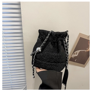 Close-up of black drawstring bucket bag with silver chain strap and silk tassel detail