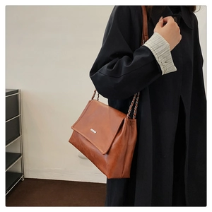 Detail of vintage brown tote bag with oily texture leather and silver chain strap