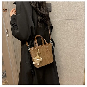 Brown quilted leather bucket bag styled with black coat and cute plush toy accessory