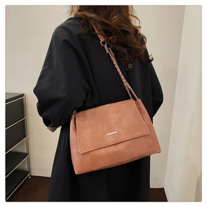 Detailed side view of vintage brown leather tote bag with silver metal bar on a model