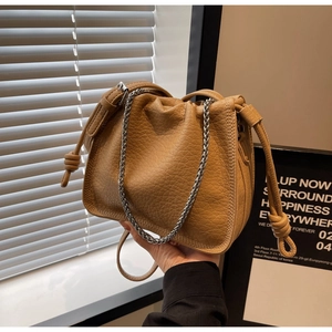 Detail showing the lychee grain texture and knotted strap on this khaki bucket bag