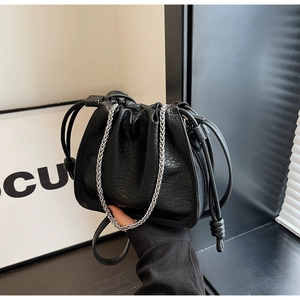 Detail of black lychee grain bucket bag with silver chain and drawstring closure