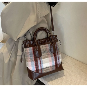 Détail du sac seau en tweed vintage avec bordures en cuir marron et fermeture à cordon