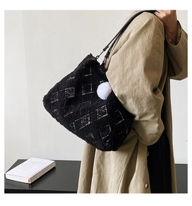 Detail of black faux shearling tote bag with white quilted pattern and fluffy pom pom