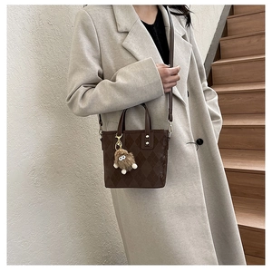 Detail of brown argyle pattern crossbody bag with gold hardware and plush charm