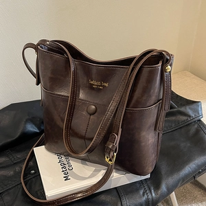 Retro dark brown bucket bag with gold lettering on elegant black leather and book background