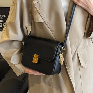 Fashionable black leather crossbody bag with gold hardware and trendy charm decoration