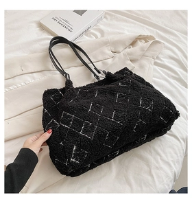Detail of black lamb wool tote bag with white grid patterns on light background
