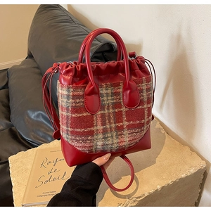 Détail du sac seau à carreaux rouge et blanc avec fermeture à cordon sur surface en pierre