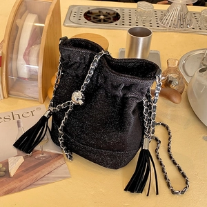 Sparkly black bucket bag with silver chain strap and fringe details in a cafe setting