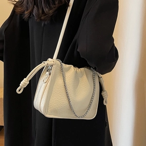 Chic off-white lychee grain leather bucket bag with silver chain and crossbody strap