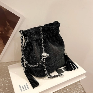 Sparkly black bucket bag with glitter finish and chain strap on a white book