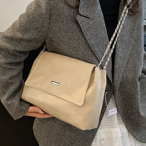 Elegant beige leather tote bag with silver chain strap shown on model in grey blazer