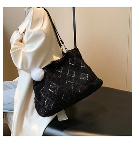 Detail of black lamb wool tote bag with white quilted stitching and soft pompom charm