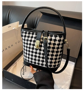 Détail du sac seau en pied-de-poule avec bordure en cuir noir dans un coffret cadeau