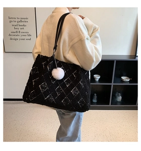 Detail of black lamb wool tote bag featuring white diamond pattern and a plush pompom