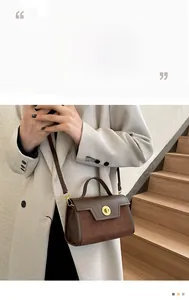 Detail view of brown leather and suede crossbody bag with golden circular metal lock