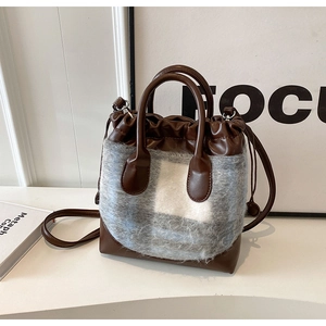 Détail de la texture pelucheuse à carreaux et garniture en cuir brun du sac seau