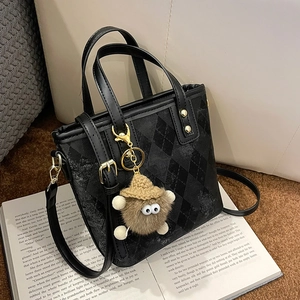 Retro black quilted bucket bag with adjustable shoulder strap and cute monster pendant