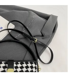 Vue détaillée du sac bandoulière en pied-de-poule avec bordure en cuir noir et boucle dorée