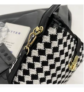 Détail de la texture pied-de-poule et des finitions métalliques dorées de ce sac chic