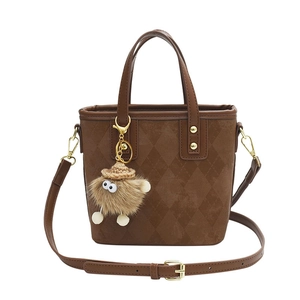 Brown quilted velvet bucket bag with plush charm and adjustable shoulder strap