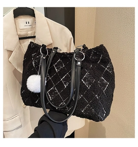 Detail view of black fleece tote bag with white diamond stitching and plush charm