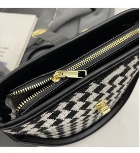 Gros plan sur la fermeture éclair en métal doré et le tissu en pied-de-poule du sac