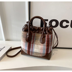 Détail du sac seau en tweed à carreaux avec poignées en cuir et cordon de serrage