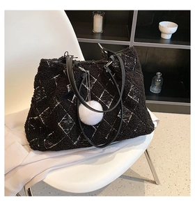 Close-up of fluffy black and white plaid lamb wool tote bag with soft plush ball charm