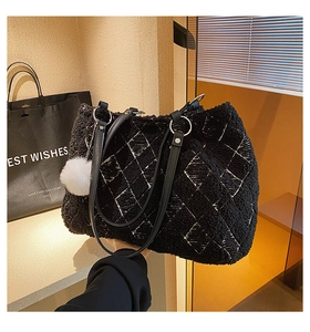 Detail of black lamb wool tote bag featuring white quilted stitching and plush ball charm