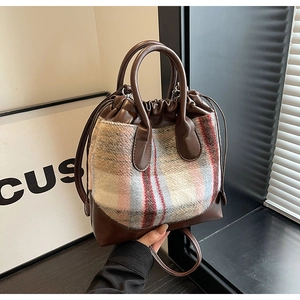 Détail du sac seau en cuir PU marron et coutures en tissu de laine à motif écossais