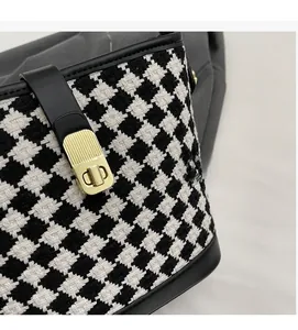 Détail du tissu pied-de-poule noir et blanc avec lanière en cuir et boucle dorée chic