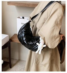 Detail der schwarzen Stepptasche mit gestreiftem Gurt und Hasen-Plüschanhänger am Model