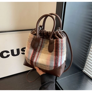 Détail du sac seau en tweed et cuir avec cordon de serrage et deux poignées rondes